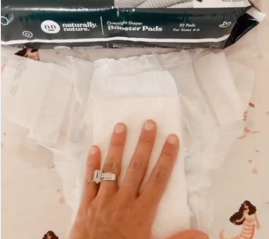 Mother placing a Naturally Nature booster pad in a diaper