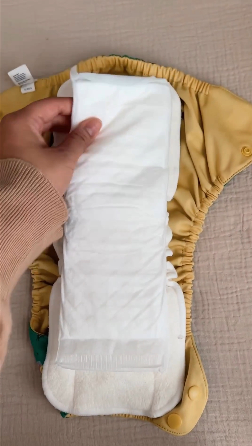 A Naturally Nature booster pad placed inside a cloth diaper for extra overnight absorbency