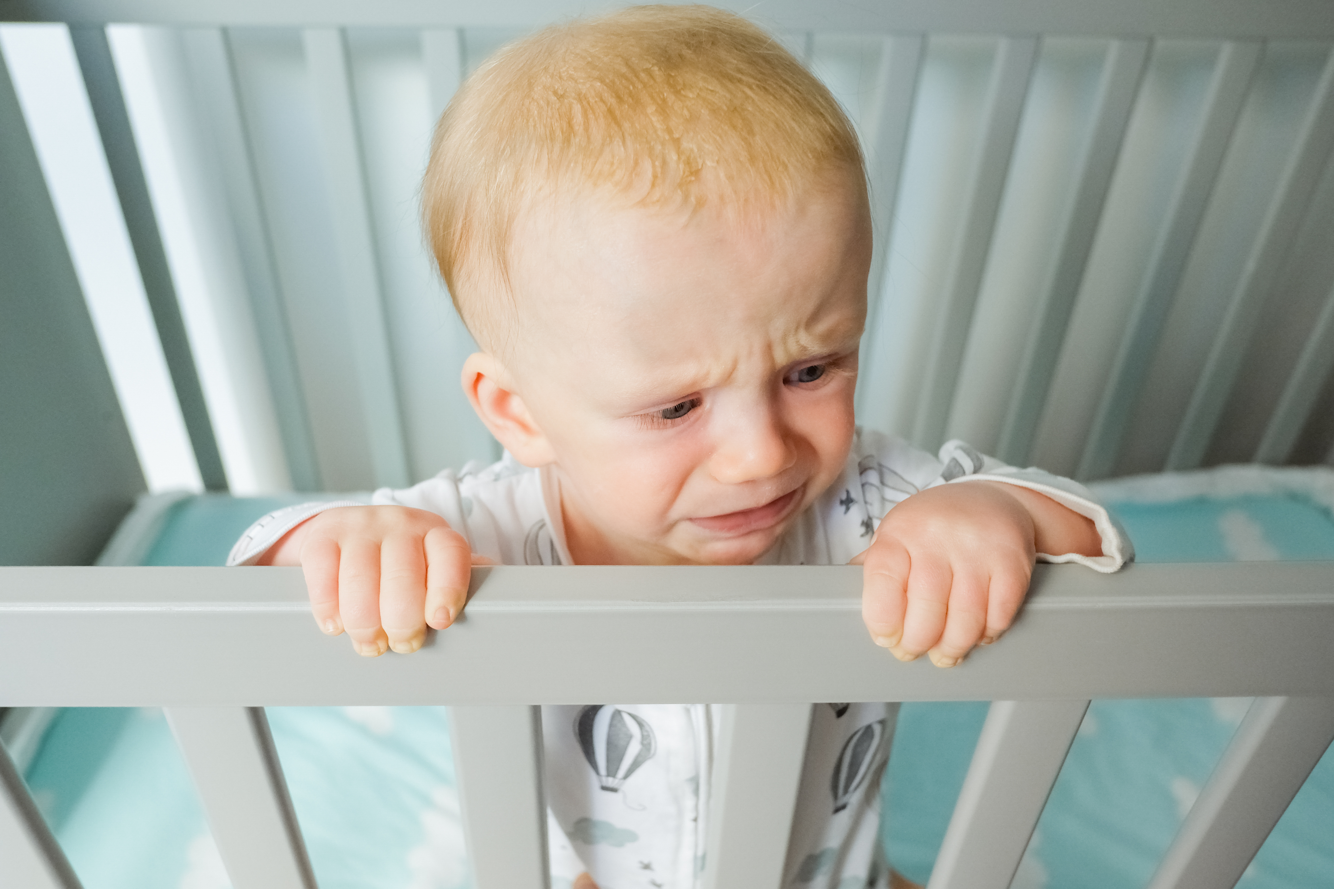 Worried baby standing in crib